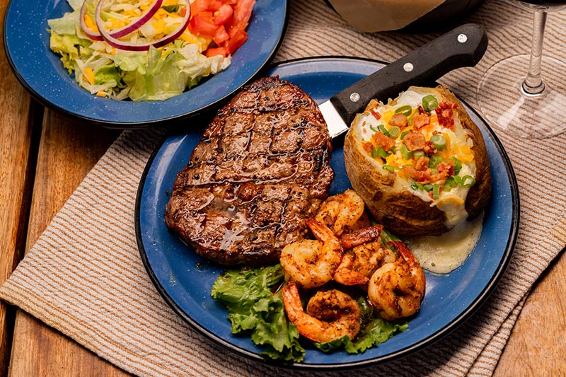 Our 10 oz. Certified Angus Beef Ribeye paired with five jumbo grilled shrimp served with a loaded baked potato